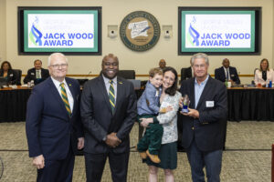 Photo of Becky Howick holding her son standing with George Mason University President Gregory Washington, Rector Michael Meese, and John Wood.