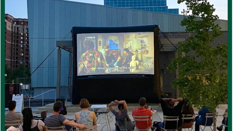 Saturday Shuffle A group of people watching an outdoor movie on the Plaza at Mason Square.