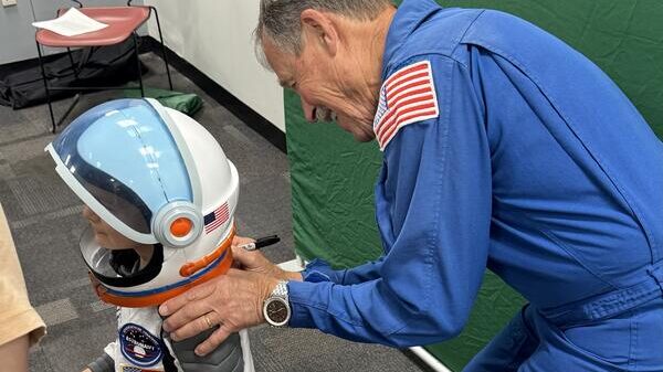 George Mason Space Day 2026 Astronaut placing space helmet on young boy at George Mason's Space Day.